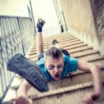 man in blue t-shirt and blue denim shorts sitting on concrete stairs during daytime