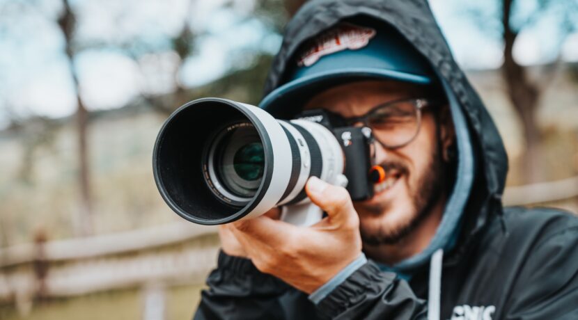 man in black jacket holding black dslr camera