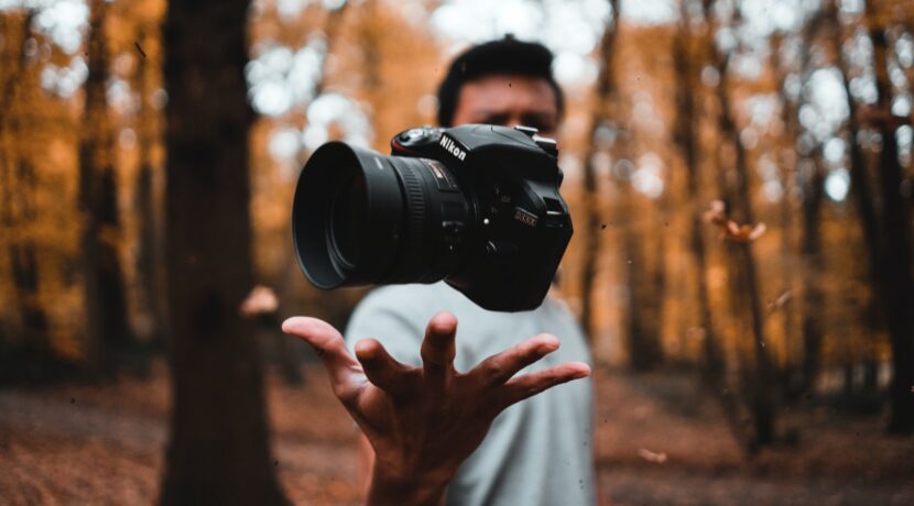 black DSLR camera floating over man's hand at the woods
