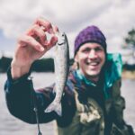 depth photography of man holding fish