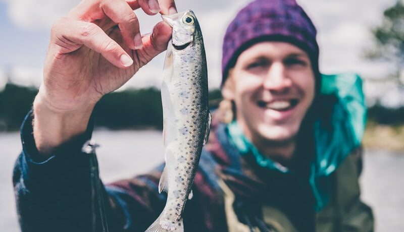 depth photography of man holding fish
