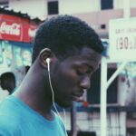 man wearing blue crew-neck shirt wearing earbuds