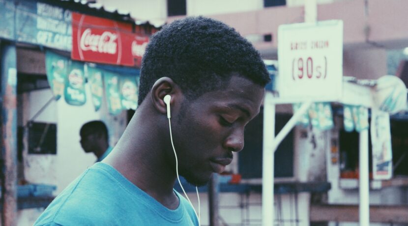 man wearing blue crew-neck shirt wearing earbuds