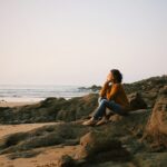 woman sitting near sea during daytime