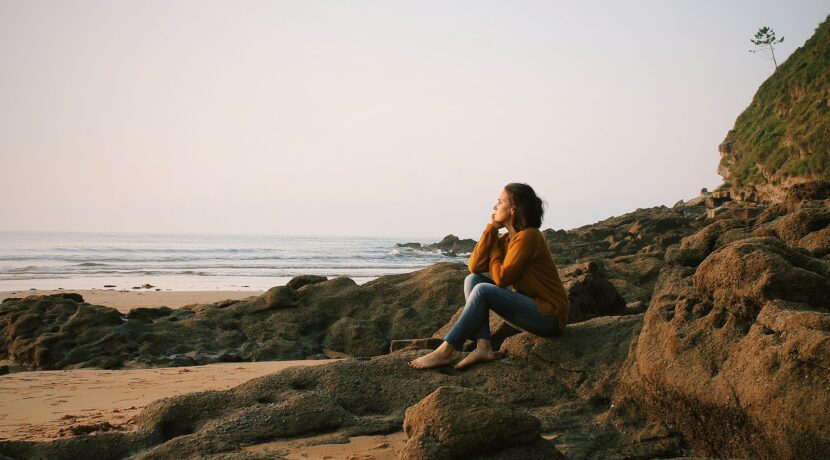 woman sitting near sea during daytime
