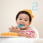 baby sitting on white chair while smiling at the camera