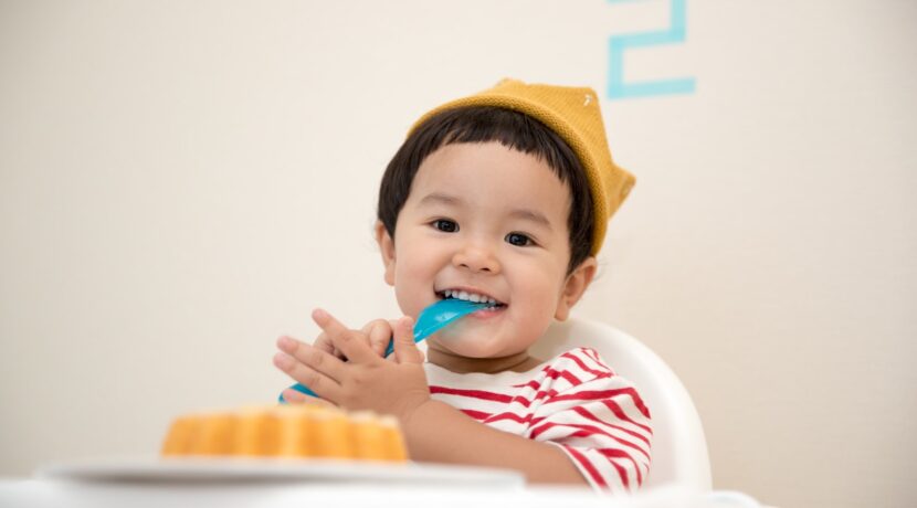 baby sitting on white chair while smiling at the camera