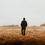 man walking on brown grass field
