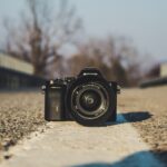 selective focus photography of black DSLR camera on gray concrete pavement during daytime
