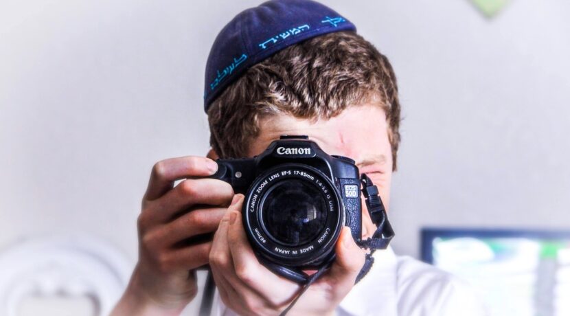 man in blue knit cap holding black and silver nikon dslr camera