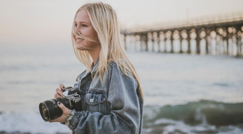 woman holding camera standing on seashore