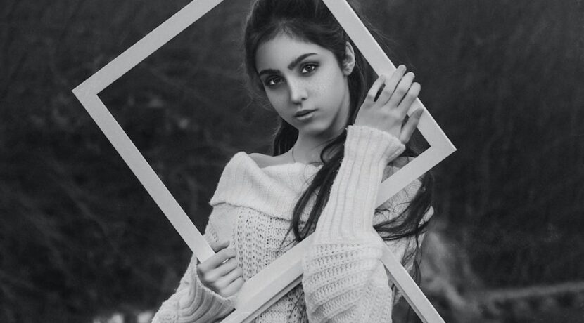 grayscale photo of girl in dress holding photo frame