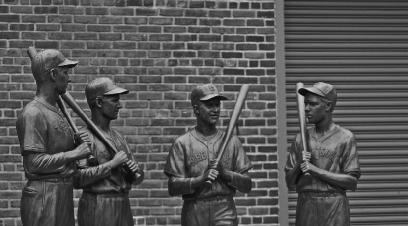 grayscale photo of 2 men standing near brick wall