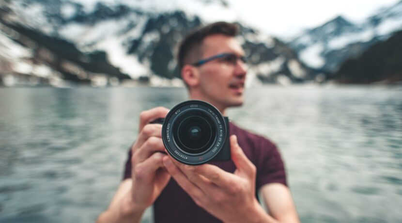 man in red crew neck t-shirt holding black camera