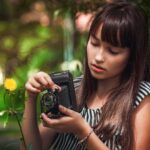 woman in black and white striped shirt holding black camera