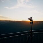 gray DSLR camera on tripod near railing