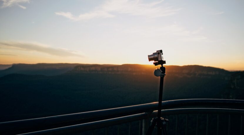 gray DSLR camera on tripod near railing