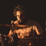 man in white shirt playing drum set