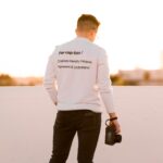 man in white top and black pants holding camera