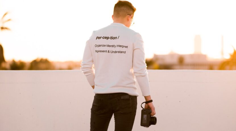 man in white top and black pants holding camera