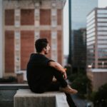 man sitting on white concrete building during daytime