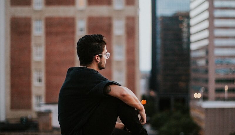 man sitting on white concrete building during daytime