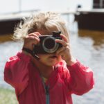 selective focus photography of girl using a camera