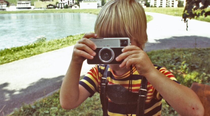 girl in yellow and black stripe shirt holding gray and black camera