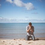 man kneeling down near shore