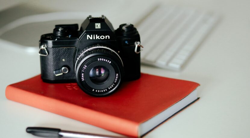black Nikon MILC camera on red book and pen