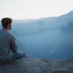 man in gray shirt sits on cliff