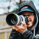 man in black jacket holding black dslr camera