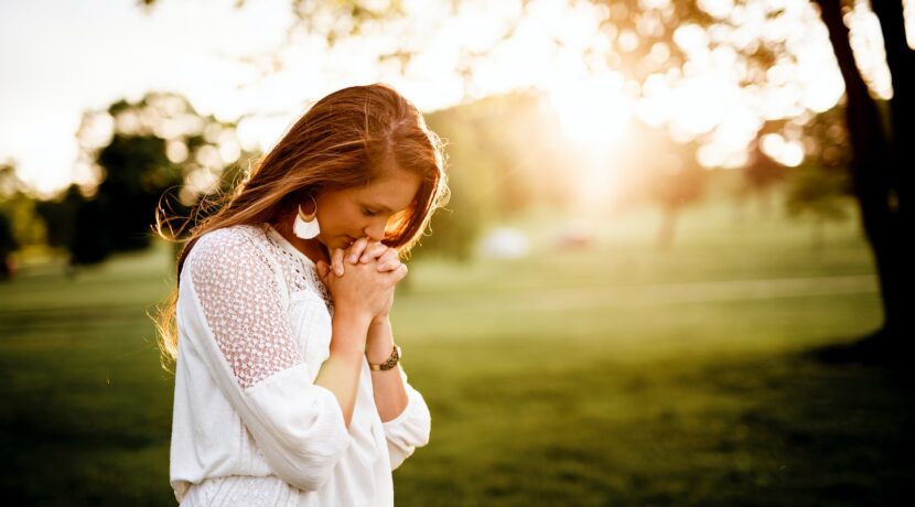 woman praying beside tree