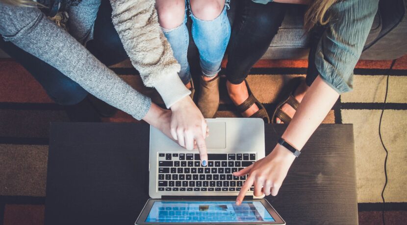 three person pointing the silver laptop computer