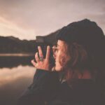 photograph of woman taking a picture of body of water