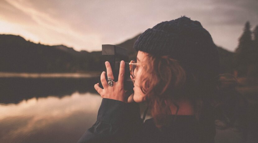 photograph of woman taking a picture of body of water