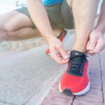 person in red nike sneakers sitting on concrete floor