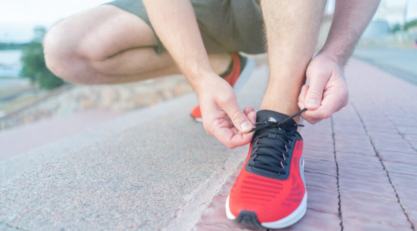 person in red nike sneakers sitting on concrete floor
