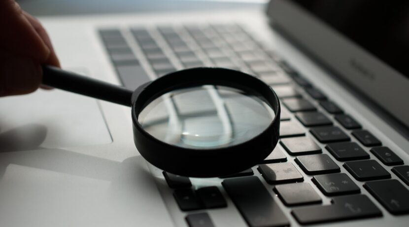 magnifying glass near gray laptop computer