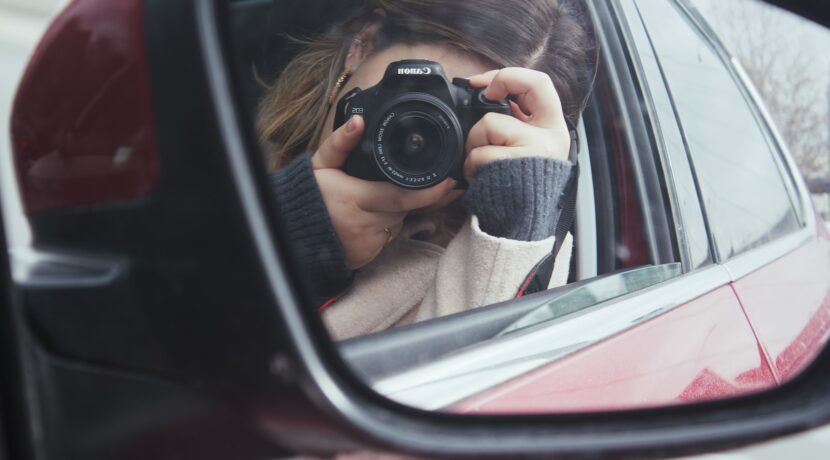 a woman taking a picture of herself in a car mirror