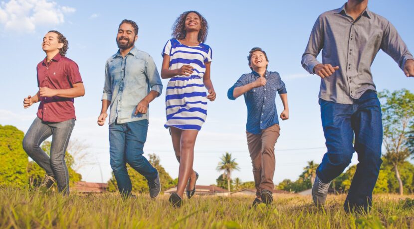 people running on grassfield under blue skies at daytime