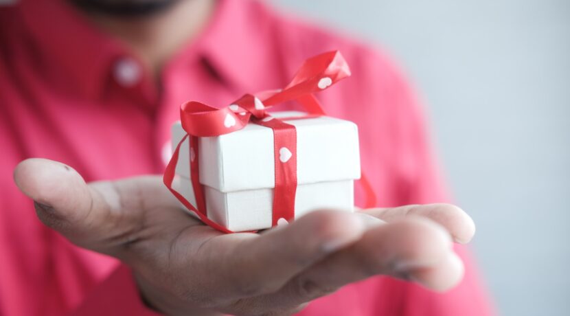 a man holding a white gift box with a red ribbon