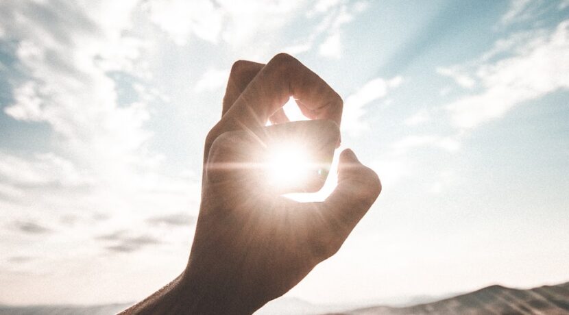 photography of sun glaring through the hole of finger