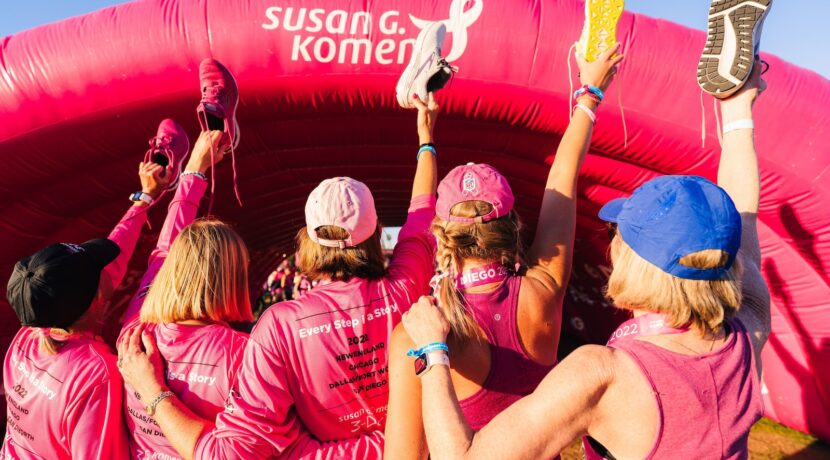 a group of women in pink shirts standing in front of a pink inflatable