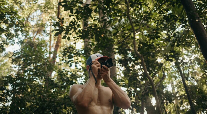 a shirtless man taking a selfie in the woods