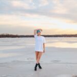 a woman in a white dress standing on a frozen lake