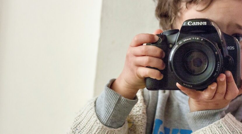 boy holding Canon DSLR camera