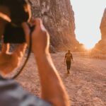 a man taking a picture of a woman in the desert