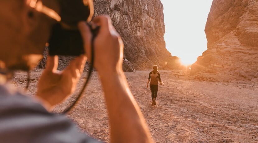 a man taking a picture of a woman in the desert