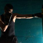 man in black tank top and black shorts wearing black boxing gloves
